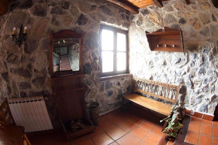 Imagen del interior de la Casa Rural Artola con un perchero y un banco de madera